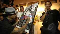 Drummer grup musik Superman Is Dead, Jrx (kiri) menandatangani foto saat pameran fotografi "Laut Luka Blues" di Galeri Foto Jurnalistik Antara , Jakarta, Jumat (22/5/2015). 51 karya foto karya Ismar Patrizki dipamerkan. (Liputan6.com/Faizal Fanani)