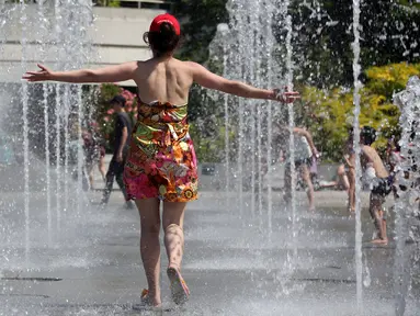 Seorang wanita menyegarkan dirinya di air mancur taman Andre Citroen, Paris, Senin (19/6). Suhu temperatur di ibu kota Prancis ini mencapai 36 derajat celcius. (AFP Photo / LUDOVIC MARIN)