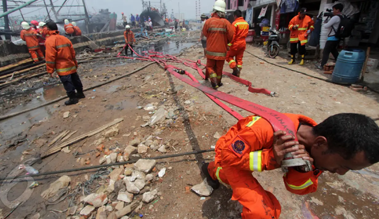 Petugas pemadam kebakaran menarik selang air usai memadamkan kapal nelayan yang terbakar di Pelabuhan Muara Angke, Jakarta, Jumat (27/2/2015). Diduga kebakaran disebabkan korsleting listrik. (Liputan6.com/Johan Tallo)