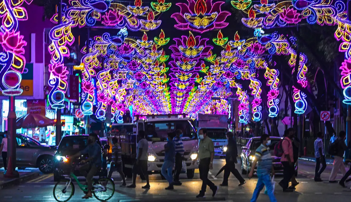 Pejalan kaki menyeberang jalan yang dihiasi dekorasi meriah menjelang Diwali, festival cahaya bagi umat Hindu, di distrik Little India di Singapura pada 23 Oktober 2020. (Photo by Roslan RAHMAN / AFP)