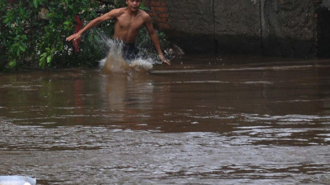 Sejumlah anak melompat pada aliran Kali Ciliwung yang mengalir deras di kawasan Bukit Duri-Manggarai, Jakarta, Selasa (2/7/2024). Merdeka.com/Imam Buhori