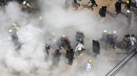 Para pengunjuk rasa bereaksi ketika mereka diliputi oleh gas air mata yang ditembakkan oleh polisi, dan ketika pengunjuk rasa lainnya melepaskan alat pemadam kebakaran, selama demonstrasi menentang kudeta militer di Yangon (6/3/2021). (AFP Photo)