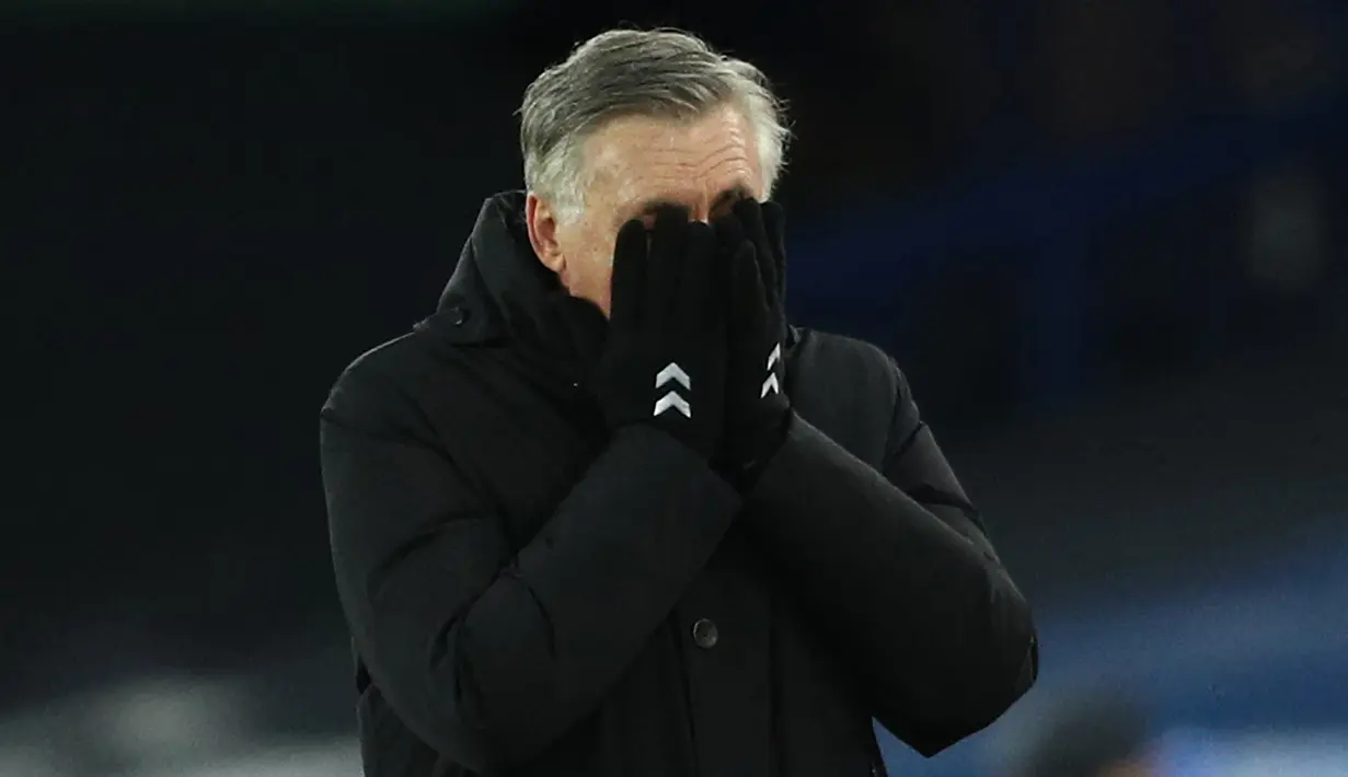 Manajer tim Everton, Carlo Ancelotti tampak kecewa dengan menutupi mukanya dalam laga lanjutan Liga Inggris 2020/21 pekan ke-17 melawan West Ham United di Goodison Park, Jumat (1/1/2021). Everton kalah 0-1 dari West Ham United. (AFP/Jan Kruger/Pool)