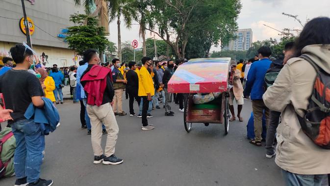 Para mahasiswa memberi jalan kepada tukang becak yang membawa kasur di tengah aksi demonstrasi di Palembang