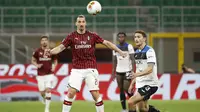Penyerang AC Milan, Zlatan Ibrahimovic, berebut bola dengan bek Atalanta, Mattia Caldara, pada laga lanjutan Serie A di Stadion San Siro, Sabtu (25/7/2020) dini hari WIB. AC Milan bermain imbang 1-1 atas Atalanta. (AP/Antonio Calanni)