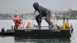 Patung perunggu terbesar di Inggris,  berjudul 'Messenger' tiba dengan tongkang di pesisir pantai Plymouth, Senin (18/3). Nantinya patung dengan tingggi 7 meter itu bakal dipajang di depan gedung teater kota, Theatre Royal. (REUTERS/Peter Nicholls)