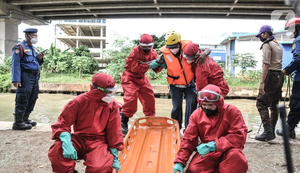 Petugas mengenakan APD saat mengevakuasi korban banjir yang terpapar Covid-19 dalam simulasi penanganan banjir di Kalimalang, Cipinang Melayu, Rabu (17/11/2021). Simulasi digelar dalam rangka kesiapsiagaan petugas dalam penanganan korban banjir.  (merdeka.com/Iqbal S Nugroho)