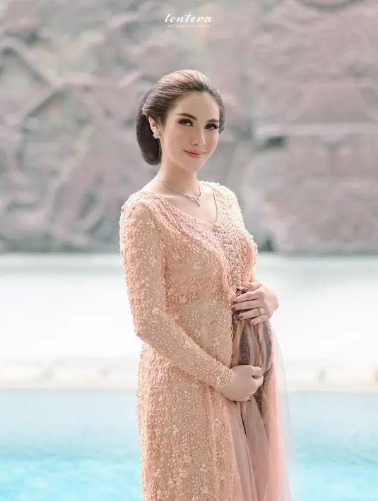 Pemeran Syahra Larez mengenakan kebaya asimetris full payet warna peach dan kain batik coklat saat gelar mitoni anak pertama. [@syahralarez_new]