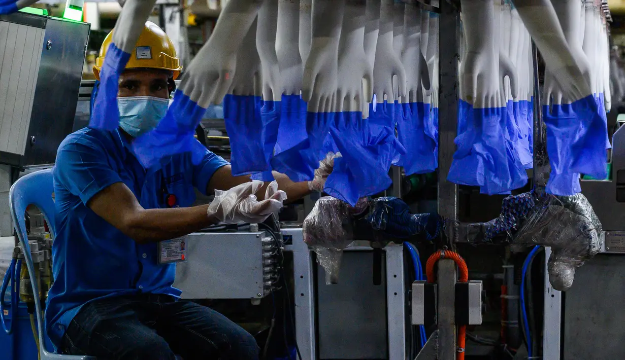 Seorang pekerja memeriksa sarung tangan sekali pakai di pabrik Top Glove di Shah Alam di pinggiran Kuala Lumpur (26/8/2020). Top Glove, sebuah perusahaan yang berbasis di Malaysia adalah salah satu produsen sarung tangan karet terbesar di dunia. (AFP/Mohd Rasfan)