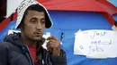 Yosri Adjili (25), seorang pengangguran, melakukan aksi mogok makan dan menjahit mulutnya ketika berunjuk rasa menuntut diberikan pekerjaan, di halaman kantor pemerintah setempat di Kasserine, Tunisia, Rabu (27/1). (REUTERS/Zohra Bensemra)