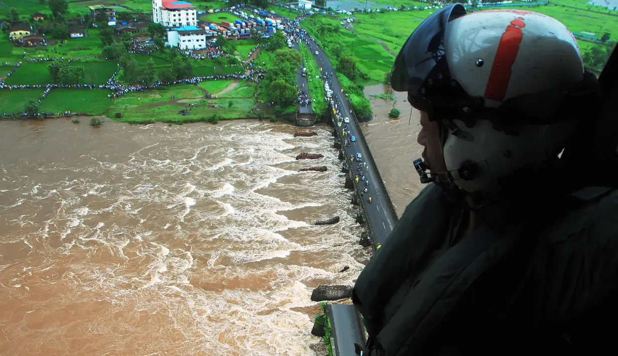 Anggota pasukan pertahanan India terlihat dari helikopter di lokasi jembatan utama yang runtuh akibat derasnya aliran sungai Savitri yang sedang meluap di barat India, Rabu (3/8). Dua bus yang membawa sedikitnya 22 penumpang terjun ke sungai itu. (AFP)