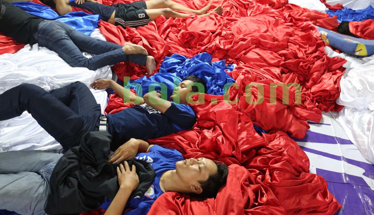 Suporter tertidur usai ikut dalam kegiatan menjahit bendera Merah-Putih raksasa di Tangerang, Sabtu (31/10/2015). Selain ingin mencatat rekor dunia, tema dasar adalah "One Soul, One Nation Untuk Sepakbola Indonesia".  (Bola.com / Nicklas Hanoatubun).