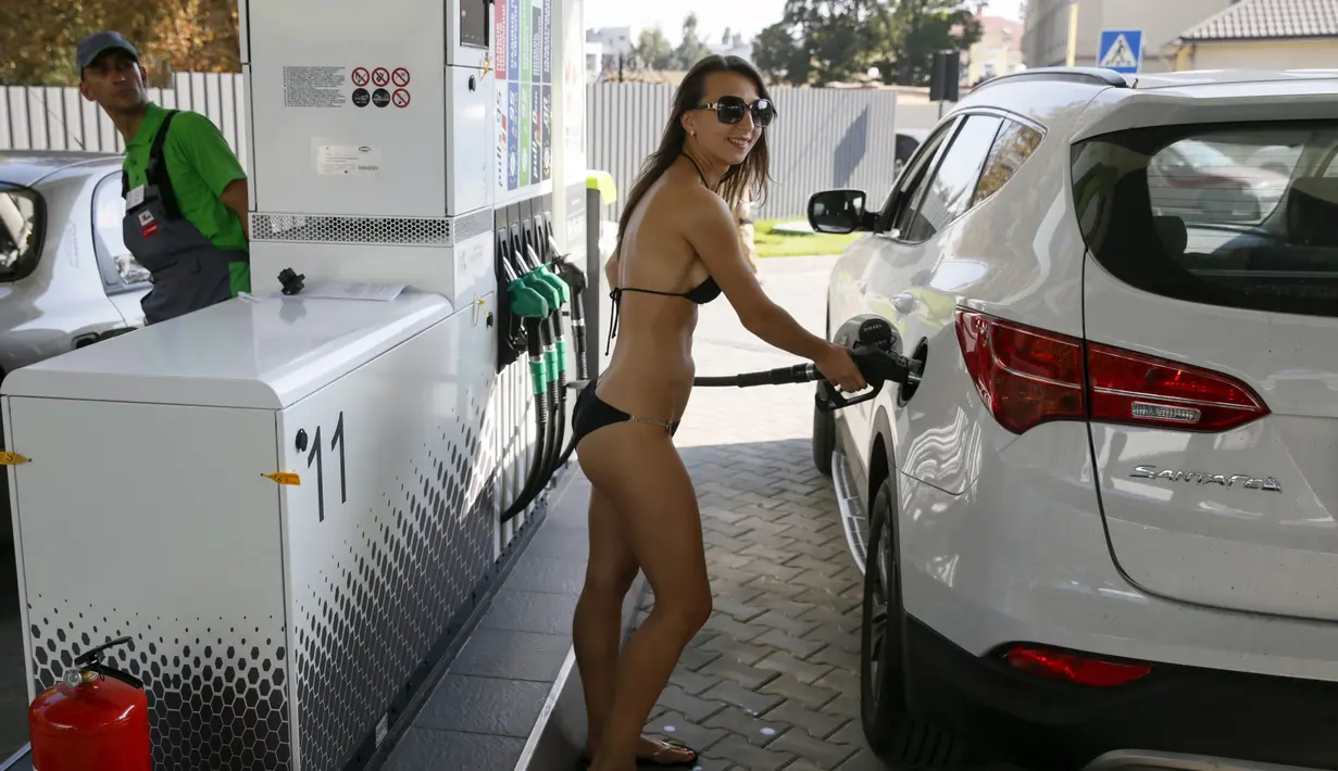 Seorang wanita mengenakan bikini saat mengisi bahan bakar untuk mobilnya di sebuah SPBU di Kiev, Ukraina, 26 September 2015. SPBU ini memberikan bensin gratis kepada pelanggan wanita yang datang dengan hanya mengenakan bikini. (REUTERS/Valentyn Ogirenko)