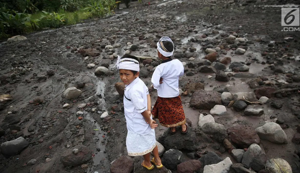 Dua anak melihat lahar dingin saat akan beribadah di sekitar Sungai Yeh Sah, Desa Batusesa, Kec Rendang, Karangasem, Bali, Jumat (1/12). Warga berharap diberi keselamatan dan berkah dari erupsi Gunung Agung yang terjadi. (Liputan6.com/Immanuel Antonius)