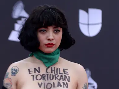 Penyanyi Chile Mon Laferte berpose di karpet merah Latin Grammy Awards 2019, MGM Grand Garden Arena, Las Vegas, Amerika Serikat, Kamis (14/11/2019). Mon menuliskan kalimat 'Di Chile mereka menyiksa, memperkosa, dan membunuh' di tubuhnya. (Bridget BENNETT/AFP)