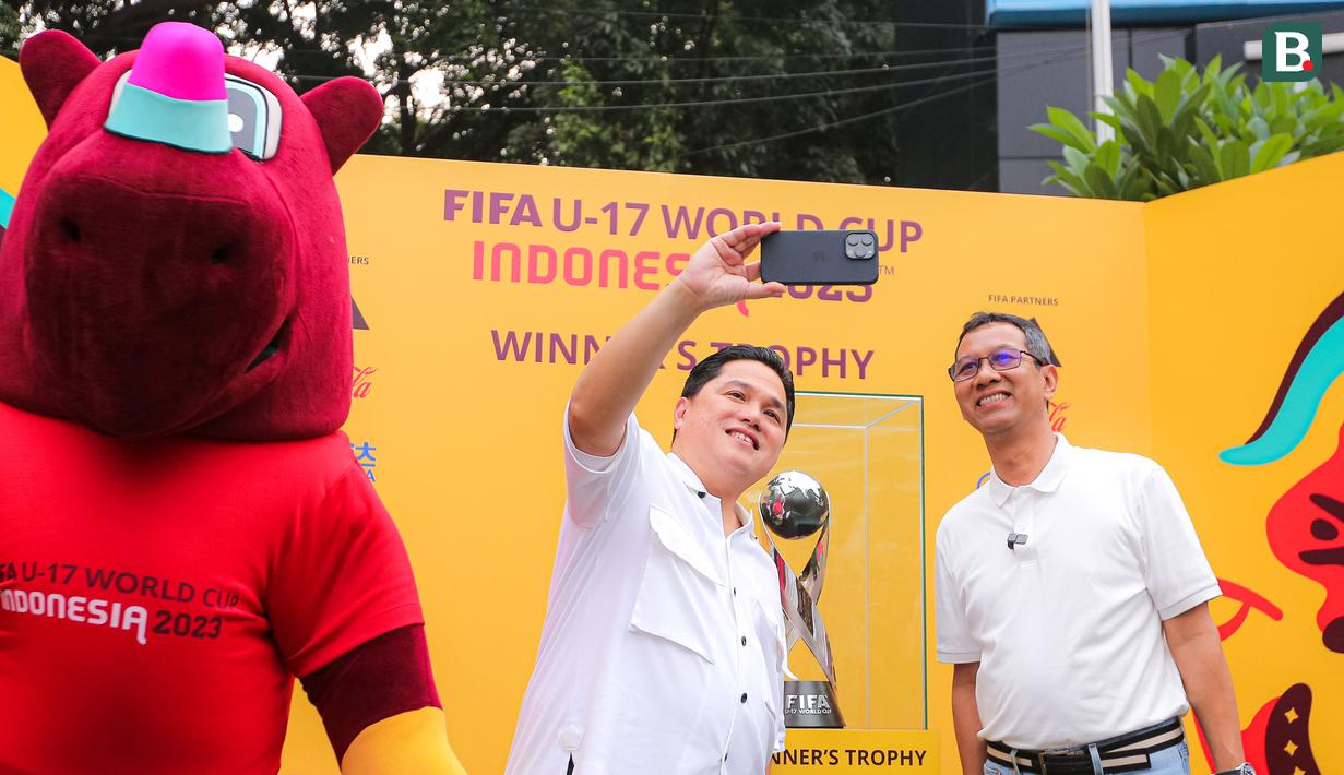 <p>Ketua PSSI, Erick Thohir (tengah), melakukan swafoto bersama Penjabat (Pj) Gubernur DKI Jakarta, Heru Budi Hartono (kanan), saat memamerkan trofi Piala Dunia U-17 2023 kepada masyarakat di Bundaran Hotel Indonesia (HI), Jakarta, Minggu (15/10/2023). (Bola.com/Bagaskara Lazuardi)</p>