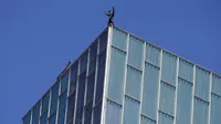 Pemanjat asal Prancis Alain Robert, melambaikan tangan setelah berhasil memanjat Melia Barcelona Sky Hotel di Spanyol, Senin (12/6). Pria 55 tahun itu butuh waktu 20 menit untuk memanjat gedung setinggi 116 meter tanpa pengaman. (AP Photo/Manu Fernandez)