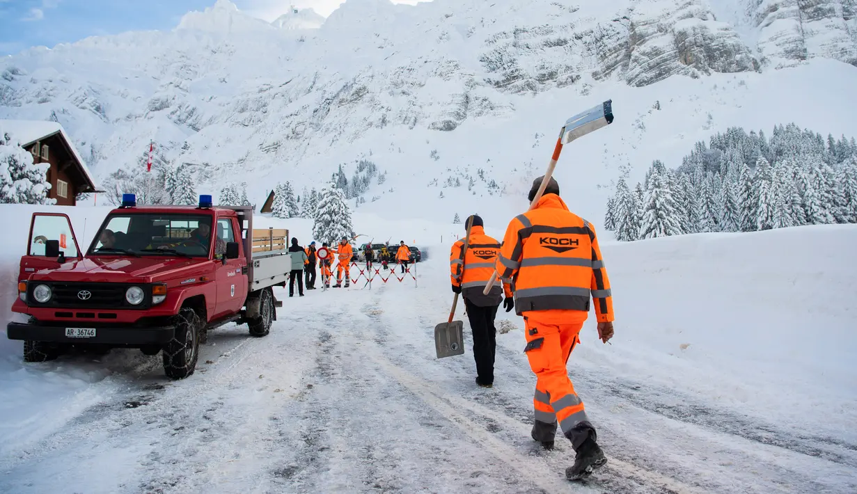 Petugas membawa sekop untuk membersihkan longsoran salju yang masuk ke dalam Hotel Saentis di Schwaegalp, Swiss, Jumat (11/1). (Gian Ehrenzeller/Keystone via AP)