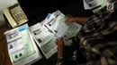 Petugas merapikan beberapa dokumen di rumah terduga penampung TKI Ilegal di Jalan Percetakan Negara X, Jakarta, Rabu (31/5). Bersama satu tersangka, petugas Dirtipidum Mabes Polri melakukan pencarian barang bukti baru. (Liputan6.com/Helmi Fithriansyah)