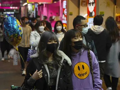 Orang-orang memakai masker untuk melindungi diri dari penyebaran virus corona, berjalan di jalan di Hong Kong (14/1/2022). Hong Kong akan menangguhkan penerbangan transit dari sekitar 150 negara dan wilayah yang dianggap berisiko tinggi karena virus corona selama sebulan penuh. (AP Photo/Kin Cheung)