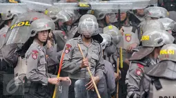 Petugas kepolisian menggunakan tameng untuk berteduh dari hujan saat menjaga aksi Hari Buruh di Jalan Medan Merdeka, Jakarta, Senin (1/5). (Liputan6.com/ Yoppy Renato)