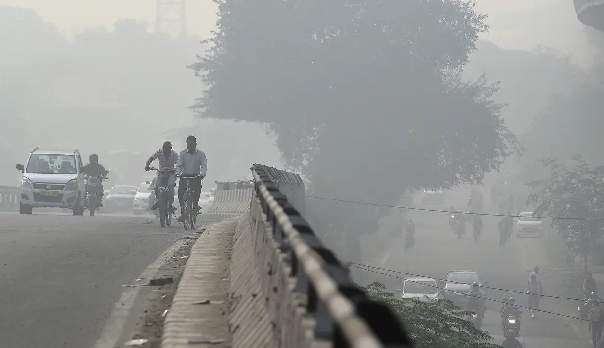 Kendaraan bermotor dan pengemudi sepeda menembus kabut asap pekat yang menyelimuti jalan di New Delhi, Selasa (12/11/2019). Kabut asap kembali menyelimuti ibu kota India setelah akhir pekan dengan udara cerah dan cuaca yang lebih baik. (Photo by Money SHARMA / AFP)