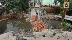 Pekerja mengangkat genteng dari dasar sungai pada jembatan yang roboh di Kali Cabang Barat Pitara, Pancoran Mas, Depok, Jumat (13/10/2023). (merdeka.com/ Arie Basuki)