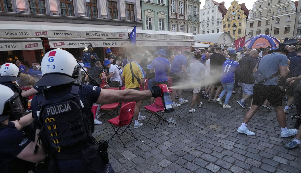 Para polisi menyemprotkan semprotan merica untuk membubarkan kericuhan antar fans menjelang laga final Conference League 2024/2025 antara Real Betis melawan Chelsea di sekitar restoran kota Wroclaw, Polandia, Selasa (27/05/2025) waktu setempat. (AP Photo/Czarek Sokolowski)