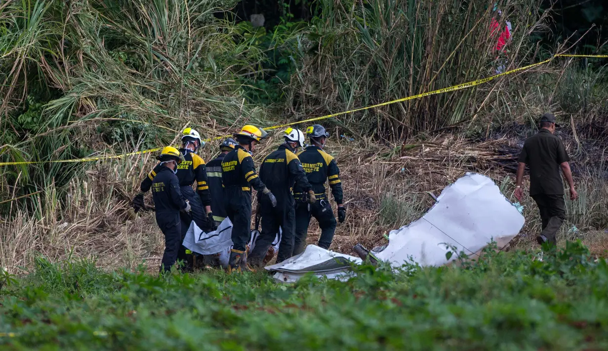 Pemadam kebakaran membawa kantong jenazah korban jatuhnya pesawat Boeing 737 di Havana, Kuba, Jumat (18/5). Terdapat 105 penumpang yang di dalamnya termasuk dari lima anak dan sembilan anggota awak pesawat. (AP Photo/Desmond Boylan)
