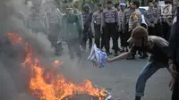 Mahasiswa gabungan se-Jabodetabek membakar ban bekas saat menggelar aksi unjuk rasa di depan Istana Merdeka, Jakarta, Selasa (16/7/2019). Dalam aksi ini sempat terjadi aksi saling dorong dengan pihak kepolisian. (merdeka.com/Iqbal S. Nugroho)