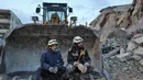 Petugas penyelamat White Helmet Suriah duduk di sebuah ekskavator saat operasi pencarian berlanjut setelah gempa mematikan di kota Sarmada, di provinsi Idlib barat laut yang dikuasai pemberontak Suriah pada 6 Februari 2023. Setidaknya 1.400 orang tewas dan 3.411 terluka di seluruh Suriah hari ini dalam gempa bumi yang berpusat di Turki barat daya, kata pemerintah dan penyelamat. (AFP/Aaref Watad)