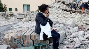 Seorang wanita duduk di antara puing bangunan yang rusak setelah gempa 6,2 SR di Amatrice, Italia tengah, Kamis (24/8). Gempa pada dini hari itu menyebabkan kerusakan besar dan getarannya membuat panik penduduk yang sedang tertidur. (REUTERS/Remo Casilli)