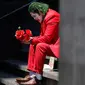 David Vazquez, seniman jalanan berpakaian seperti Joker menunggu dengan harapan pejalan kaki akan membayar berfoto dengannya di Mexico City (23/3/2020). Meluasnya penyebaran COVID-19, membuat warga canggung untuk berfoto dengan Vazquez yang merupakan pelatih di gym. (AP Photo/Rebecca Blackwell)