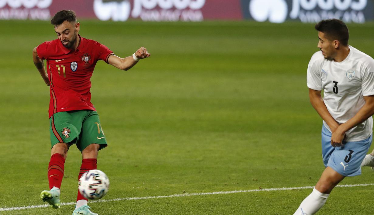 Gelandang Portugal, Bruno Fernandes (kiri) melepaskan tendangan yang berbuah gol keempat Portugal ke gawang Israel dalam laga uji coba menjelang Euro 2020 di Jose Alvalade Stadium, Lisbon, Rabu (9/6/2021). Portugal menang 4-0 atas Israel. (AP/Armando Franca)