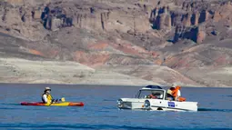 Keluarga Baker menaiki mobil amfibi Amphicar 1965 saat festival Las Vegas Amphicar Swim di Danau Mead, Nevada, Jumat (9/10). (REUTERS/Steve Marcus)