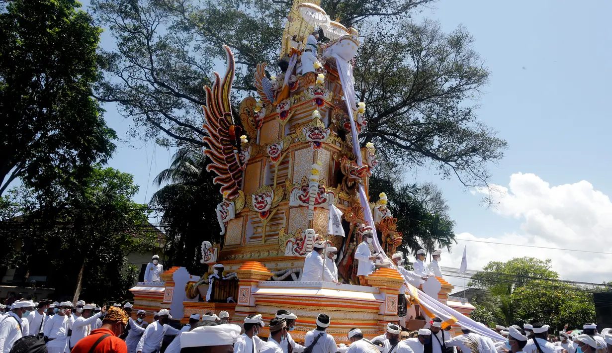 Kerumunan orang menyaksikan arak-arakan menara usungan jenazah Ida Pedanda Nabe Gede Dwija Ngenjung saat upacara Ngaben di Denpasar, Bali, Jumat (8/10/2021). Upacara Ngaben itu sebagai penghormatan terakhir terhadap seorang pemuka agama Hindu di Bali. (AP Photo/Firdia Lisnawati)