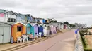 Orang-orang duduk di luar gubuk pantai di Walton-on-the-Naze, di Inggris pada 15 Juli 2021. Gubuk kayu yang dicat cerah berjajar di garis pantai Inggris telah menikmati booming selama pandemi, ketika orang-orang menemukan kembali tempat istirahat di tepi pantai di dekat rumah. (Justin TALLIS/AFP)