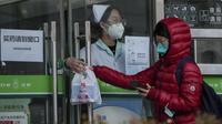 Seorang perempuan mengumpulkan kit antigen COVID-19 dari seorang pekerja di apotek di Beijing, Minggu (11/12/2022).  Sejumlah kota besar mulai membatalkan kendali antivirus dari kebijakan nol-Covid negara tersebut sejak pekan lalu karena protes massa. (AP Photo/Andy Wong)
