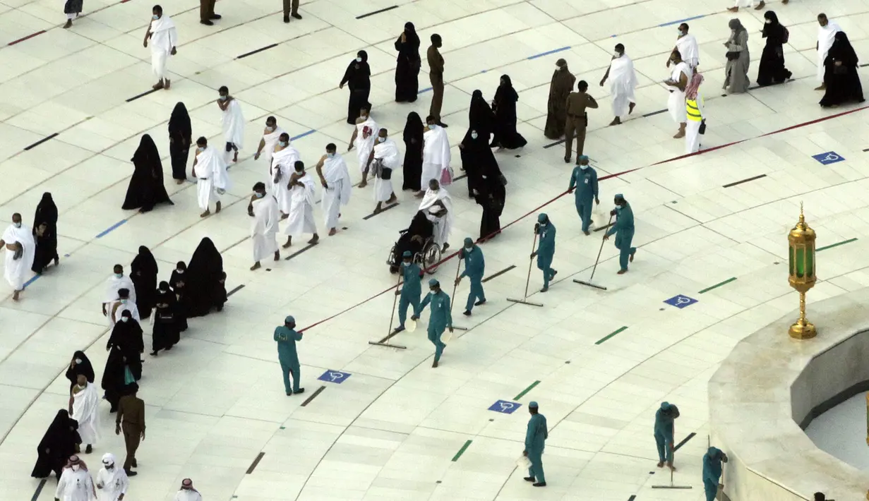Pekerja melakukan disinfeksi untuk membantu mengekang penyebaran virus corona COVID-19 saat jemaah umrah tawaf mengelilingi Ka'bah pada awal bulan suci Ramadhan di Masjidil Haram, Mekkah, Arab Saudi, Senin (12/4/2021). (AP Photo/Amr Nabil)