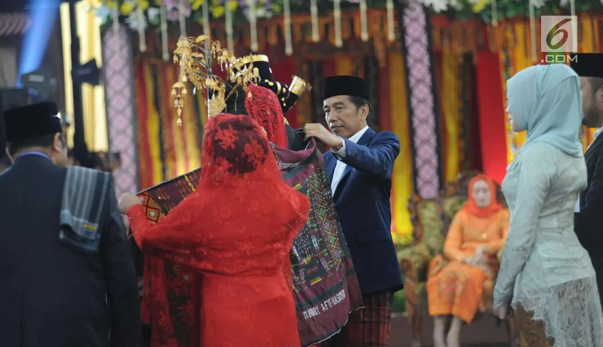 Presiden Joko Widodo dan Ibu Negara Iriana memasangkan kain ulos ke Kahiyang Ayu dan Bobby Nasution saat pesta adat di Bukit Hijau Regency Taman Setia Budi (BHR Tasbi), Medan, Sabtu (25/11). (Liputan6.com/Pool/Media Center)