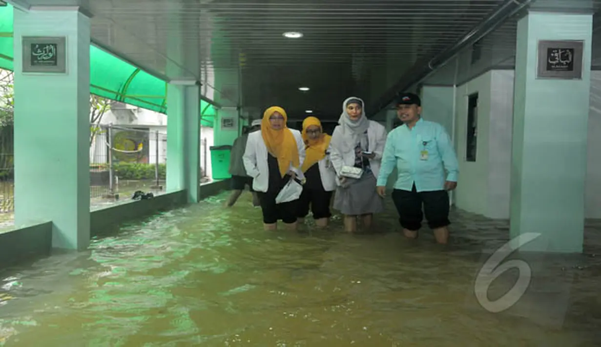 Petugas rumah sakit melintasi banjir yang menggenangi RS Islam Jakarta, Senin (9/2/2015). (Liputan6.com/Herman Zakharia)