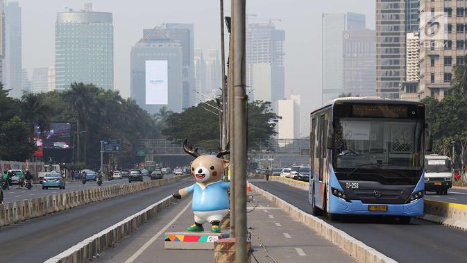 Bus Transjakarta melintas di samping patung maskot Asian Games 2018 yang menghiasi Jalan Sudirman, Jakarta, Rabu (8/8). Pemasangan maskot tersebut untuk menyemarakan Asian Games 2018 yang akan dibuka 18 Agustus 2018. (Liputan6.com/Immanuel Antonius)
