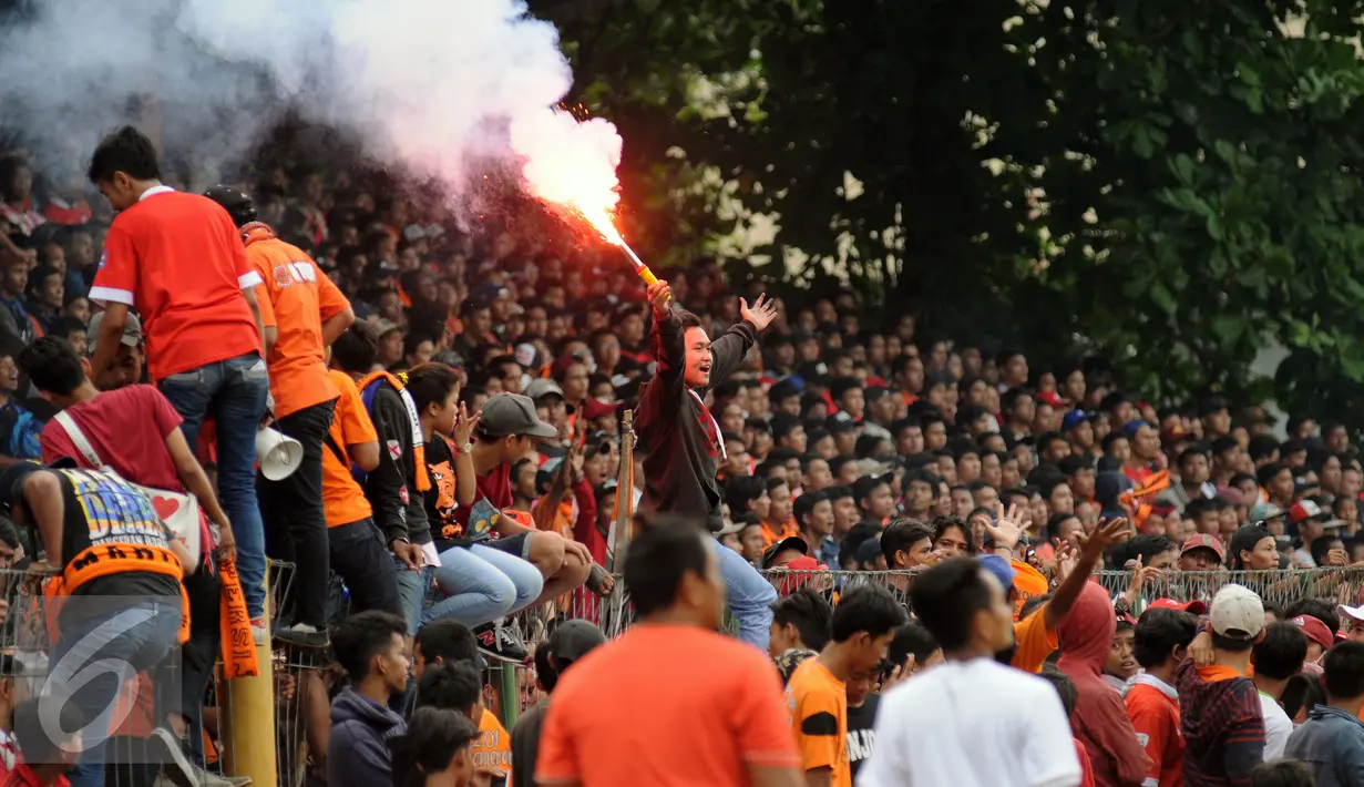 Suporter tim Macan Kemayoran menyalakan flare saat menyaksikan laga uji coba antara Persija melawan Barito Putera di Stadion Bea Cukai Rawamangun, Jakarta, Selasa (5/4/2016). Laga uji coba berakhir imbang 2-2. (Liputan6.com/Helmi Fithriansyah)