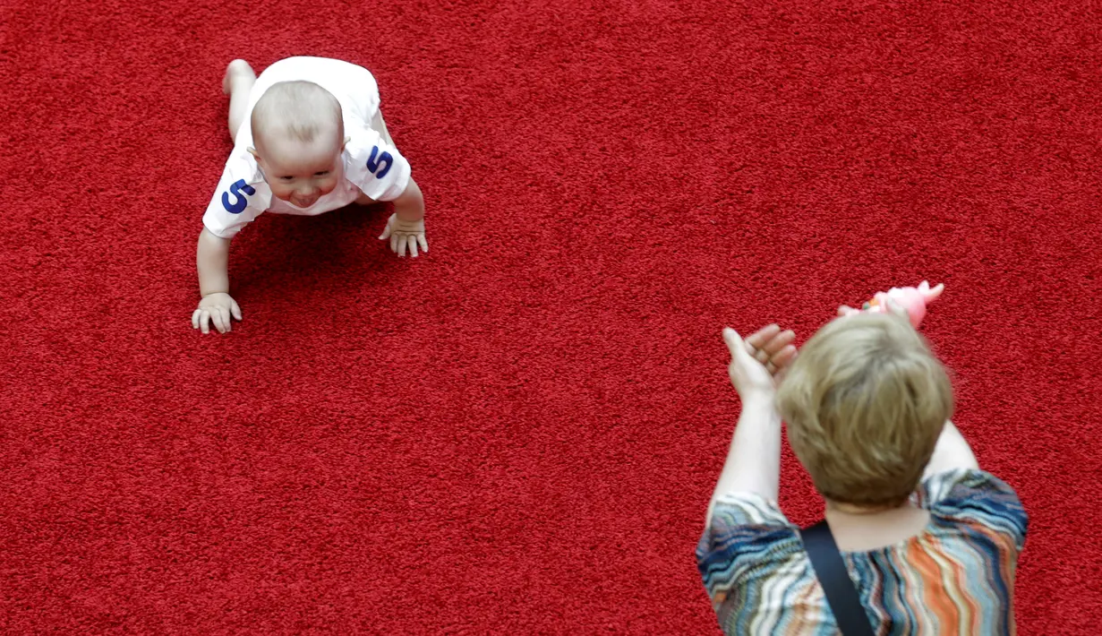 Seorang ibu memberi semangat bayinya yang sedang merangkak saat mengikuti lomba 'Balap Bayi' di Vilnius, Lithuania (1/6). Lomba ini diadakan dalam rangka memperingati Hari Anak Internasional. (REUTERS/Ints Kalnins)