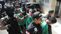 Petugas mengawal tersangka saat menggelar rilis pengungkapan 1,3 ton ganja di Polres Jakarta Barat, Kamis (4/1). Dalam penyelundupan tersebut, petugas berhasil menyita 1,3 ton ganja  dengan enam orang tersangka. (Liputan6.com/Arya Manggala)