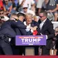 Para pengawal dari Secret Service langsung meloncat ke panggung untuk melindungi Donald Trump dan memapahnya turun.  (AP Photo/Gene J. Puskar)