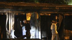 Petugas polisi dan forensik menyelidiki lokasi di rumah sakit darurat yang terbakar setelah kebakaran di kota Tetovo, Makedonia Utara, Kamis (9/9/2021). Kebakaran tersebut menewaskan sedikitnya 10 pasien. (AP Photo/Boris Grdanoski)