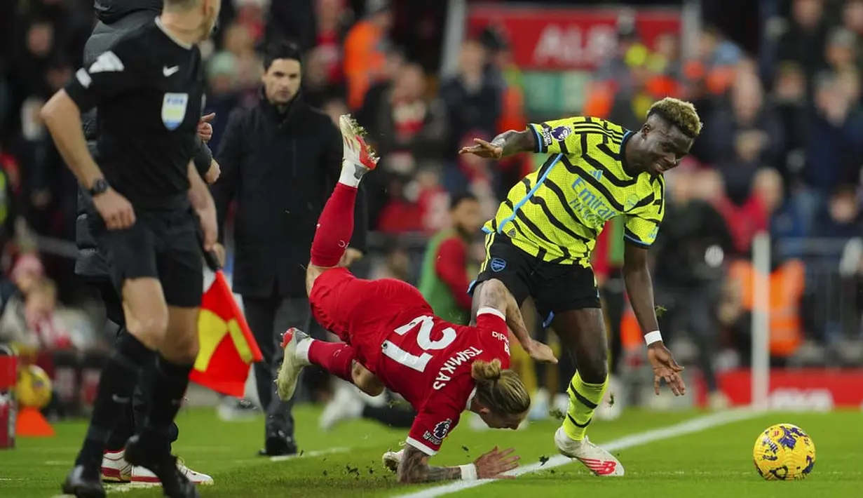 Pemain Liverpool, Kostas Tsimikas, berebut bola dengan pemain Arsenal, Bukayo Saka pada laga pekan ke-18 Premier League 2023/2024 di Stadion Anfield, Minggu (24/12/2023). (AP Photo/Jon Super)