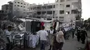 Orang-orang melintasi pedagang Palestina yang berjualan di samping puing-puing bangunan di Kota Gaza, Minggu (18/7/2021). Bagi warga Palestina yang kehilangan orang-orang terkasih dalam pertempuran antara militan Gaza dan Israel, tidak ada alasan untuk merayakan Idul Adha. (AP Photo/Khalil Hamra)