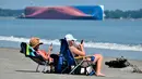 Rachel (kiri) dan Sarah Mitchell bermain ponsel saat berjemur dengan pemandangan kapal kargo Golden Ray yang terbalik di lepas pantai negara bagian Georgia, Amerika Serikat, Minggu (8/9/2019). Kapal tersebut dilaporkan memiliki 23 awak dan seorang nakhoda . (AP Photo/Terry Dickson)